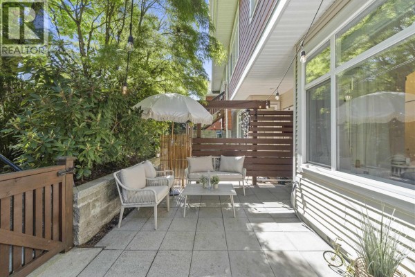 Patio space with seating, coffee table, wooden fence, and exterior view of the townhouse building. - 29 6878 Southpoint Drive, Burnaby