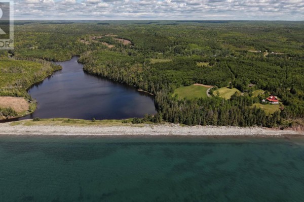 Coastal view of Manassette Lake property with a grey pebble beach, dark water, and wooded hills. - 29 Acres 344 Highway, Manassette Lake