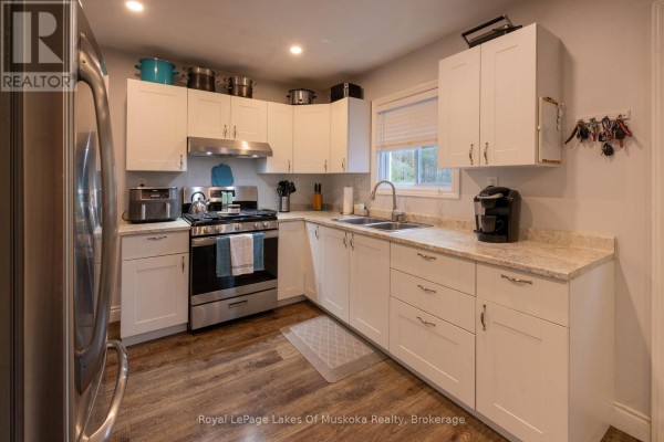 Kitchen with white cabinetry, granite countertops, stainless steel appliances, and wood-look vinyl flooring. - 29 Amylee Drive, Perry