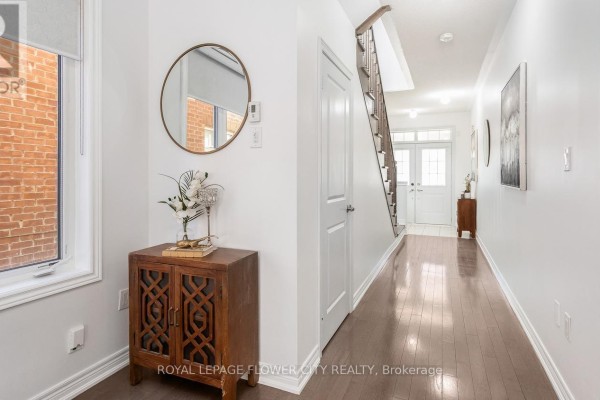 An empty room with light wood laminate flooring and a large window overlooking houses. - 29 Backwater Trail, Brampton