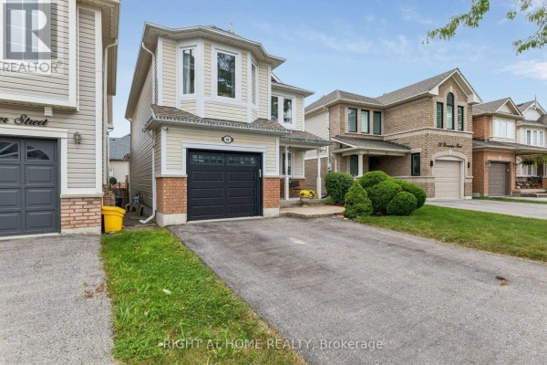 Exterior view of a two-story beige house with a black garage door and a paved driveway. - 29 Bannister Street, Clarington