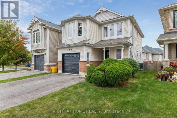 Front exterior of a beige house with a green lawn and a covered porch. - 29 Bannister Street, Clarington