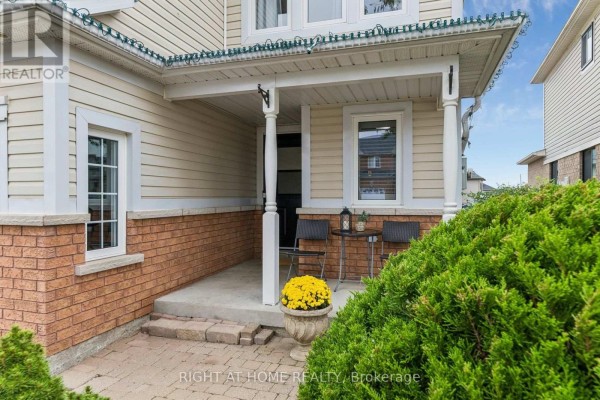 Covered front porch with brick accents, white columns, and two chairs. - 29 Bannister Street, Clarington