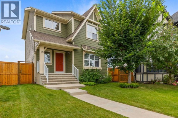 Front view of a two-story green house with a porch and manicured lawn. - 29 Brightoncrest Heights Se, Calgary