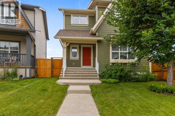 Front exterior of a two-story green house with a red door and attached garage. - 29 Brightoncrest Heights Se, Calgary