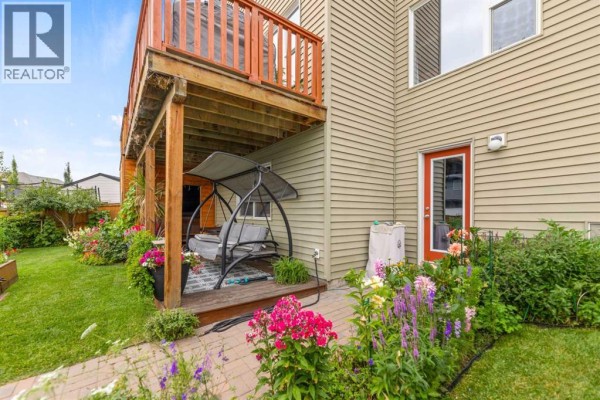 Backyard patio with a swing, viewed from the side of a beige house. - 29 Brightoncrest Heights Se, Calgary