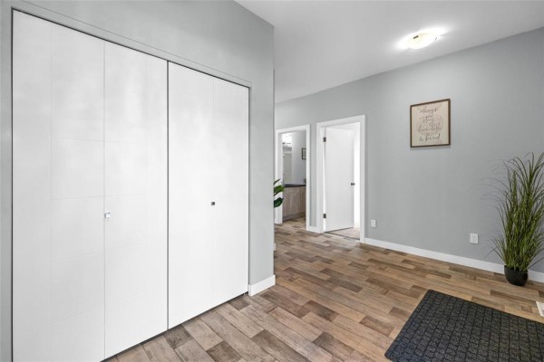 Interior hallway with light blue walls, white doors, large white bi-fold closet, and wood-look flooring. - 29 Cartmill Bay, West St Paul