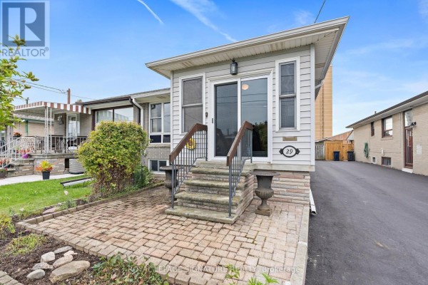 Front exterior of a house with a sunroom and paved walkway. - 29 Heavitree Drive, Toronto