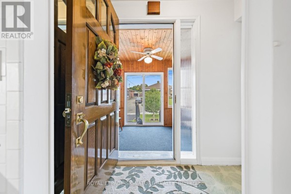 View from the front door looking into a sunroom with wooden walls and a ceiling fan. - 29 Heavitree Drive, Toronto
