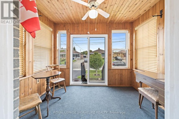 Sunroom with knotty pine wood paneling, a ceiling fan, and large windows overlooking a street. - 29 Heavitree Drive, Toronto