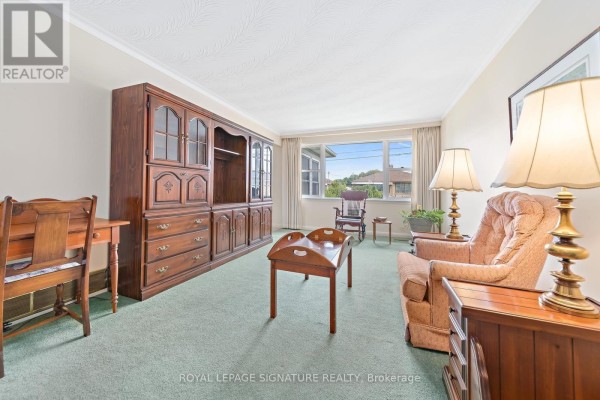 Living room with light green carpet, a large wooden entertainment unit, and upholstered furniture. - 29 Heavitree Drive, Toronto