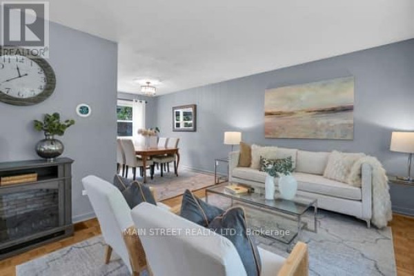 Living room with light grey walls, white sofa, fireplace, and view of dining area. - 29 Johnston Street, Georgina