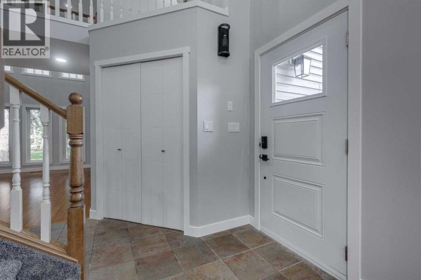 Foyer with a white front door, tiled floor, and double bi-fold closet doors. - 29 Pickwick Lane, Lacombe