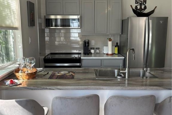 Modern kitchen with white cabinets, stainless steel sink, and appliances - 29 Railway Avenue, Pointe Du Chene