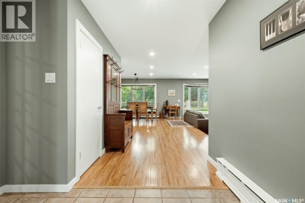 Hallway leading to an open-concept living and dining area with hardwood floors. - 29 Ridgedale Bay, White City
