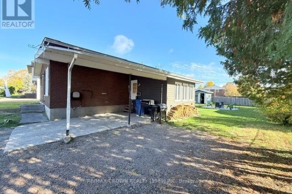 Rear exterior view of the house showing a concrete patio, barbecue, woodpile, and backyard. - 29 Seaborne Crescent, Kapuskasing