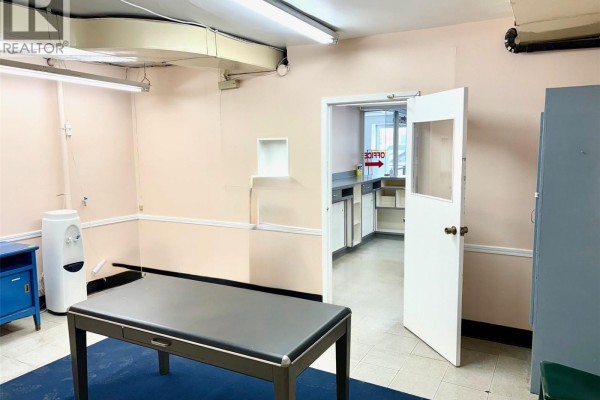 Empty room with table, light pink walls, and door leading to office area - 29 Sixth Avenue N, Yorkton