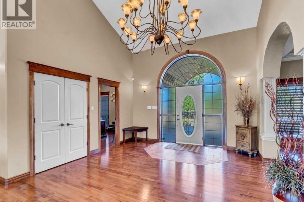 Welcoming foyer with chandelier, hardwood flooring, and arched window. - 29 Sunvalley Court Sw, Rural Cypress County
