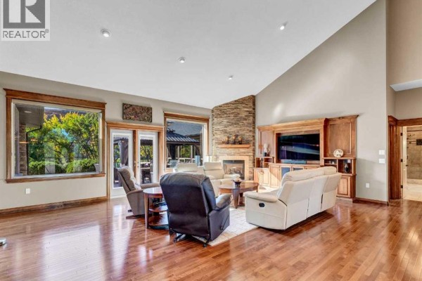 Spacious living room with hardwood floors, stone fireplace, and large windows. - 29 Sunvalley Court Sw, Rural Cypress County