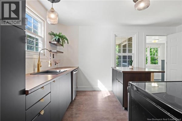 Modern kitchen with dark cabinets, wood countertops, gold fixtures, and stainless steel appliances. - 29 Wilmot Avenue, Riverview