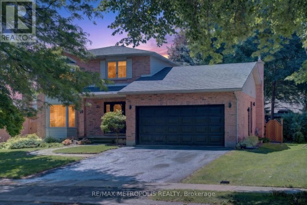 Front exterior of a brick house at twilight with illuminated windows and a black garage door. - 29 Winter Way, Brantford