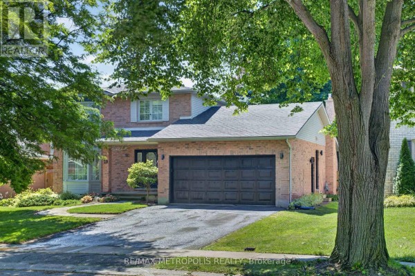 Close-up of the front exterior of a brick house with a large tree in the foreground. - 29 Winter Way, Brantford