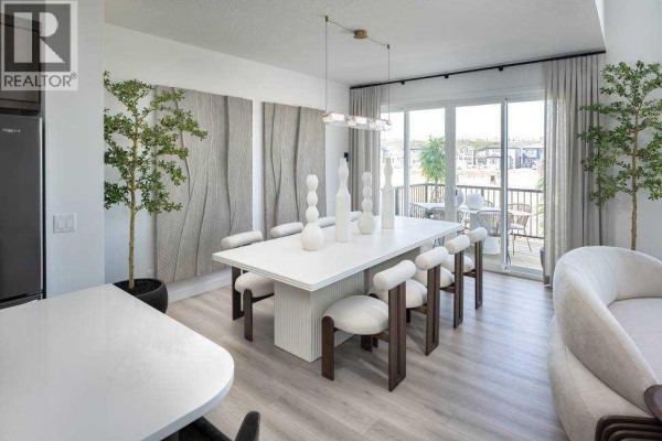 Dining area with white table, chairs, sliding glass doors, and decorative wall art. - 29 Wolf Hollow Common Se, Calgary