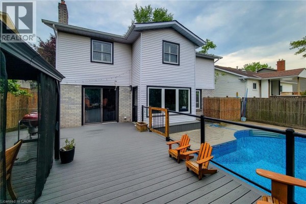 Backyard deck with lounge chairs overlooking a blue swimming pool and covered gazebo. - 29 Woodside Square, Fonthill
