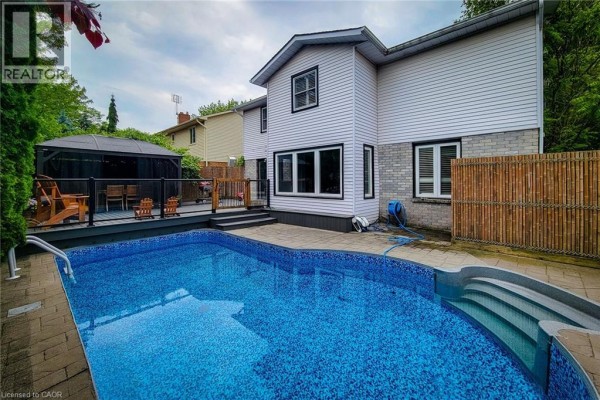 View of the backyard patio and pool area with a two-story house in the background. - 29 Woodside Square, Fonthill