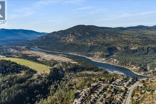 Panoramic aerial view of a town nestled beside a wide river, surrounded by forested mountains. - 290 8th Avenue, Montrose