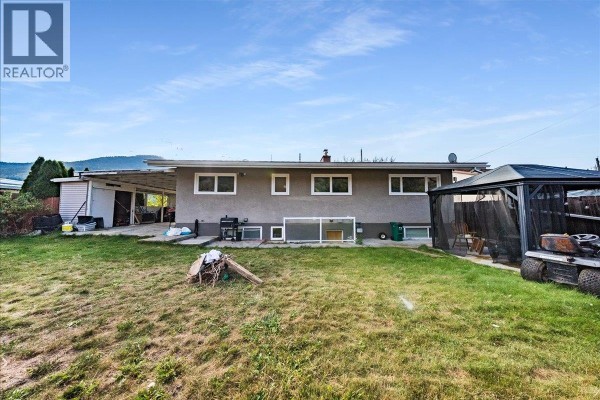 Backyard of the house showing a grassy lawn, a covered patio, and a gazebo with outdoor seating. - 290 8th Avenue, Montrose