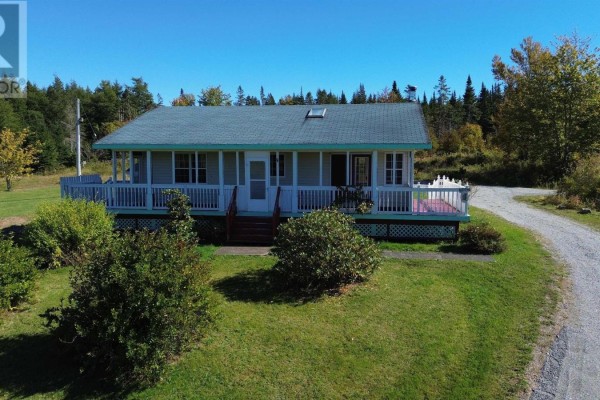 Front exterior of a light-colored house with a wrap-around porch and white railing. - 290 Macvicar Road, Enon