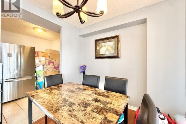 Dining table and chairs with view into kitchen area and stainless steel refrigerator. - 2900 Battleford Road Unit# 1013, Mississauga