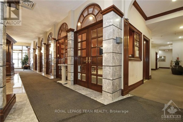 A building lobby with marble floors, carpeted runners, and double wooden glass doors. - 2903 - 1480 Riverside Drive, Ottawa
