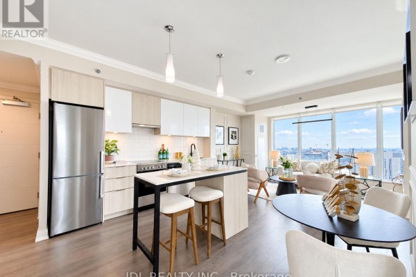 Open concept kitchen and living area with a stainless steel fridge and island with stools. - 2904 - 203 College Street, Toronto