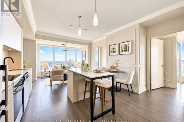View of the kitchen island, dining area, and living room from the kitchen. - 2904 - 203 College Street, Toronto