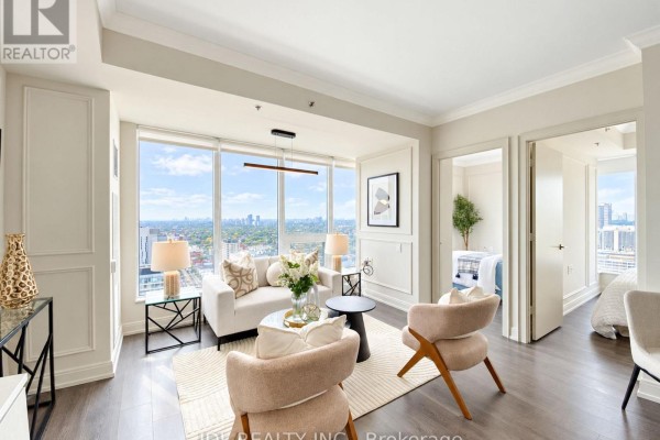 Living room and hallway entrance to a bedroom, with large windows and city views. - 2904 - 203 College Street, Toronto