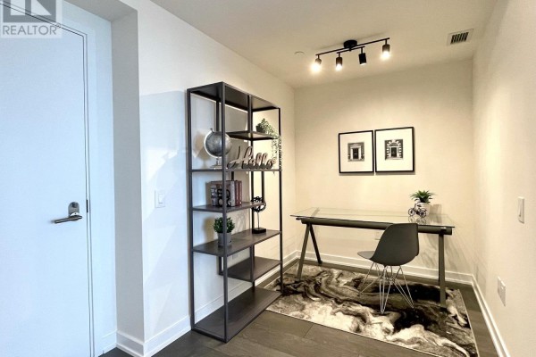 Home office with glass desk, chair, shelving unit, and two framed prints. - 2908 - 28 Freeland Street, Toronto