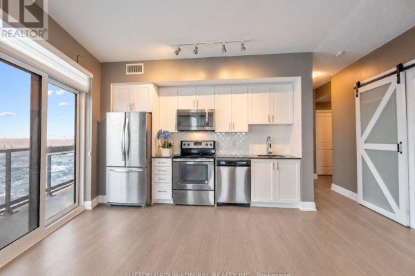 Open-concept living and kitchen area with white cabinets, stainless steel appliances, and a sliding door to the balcony. - 2908 - 3600 Highway 7, Vaughan
