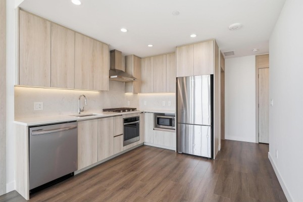 View of the apartment kitchen with light wood cabinets, stainless steel appliances, and a refrigerator. - 2908 10750 135a Street, Surrey