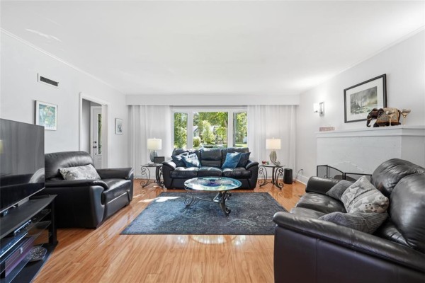 Living room with black leather furniture, a glass coffee table, and a large window. - 291 Campbell Street, Winnipeg