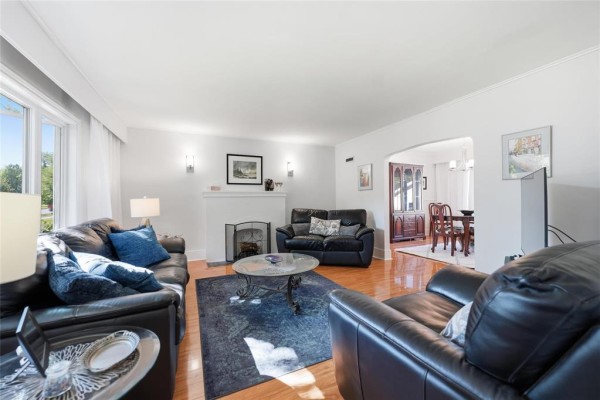 Living room showing seating area, fireplace, and arched doorway to dining room. - 291 Campbell Street, Winnipeg