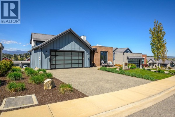 Driveway and garage of the modern home with surrounding landscaping and neighbors. - 291 Grange Drive, Vernon