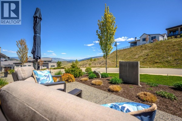 Patio seating area with an outdoor sofa and a view of the hilly landscape. - 291 Grange Drive, Vernon
