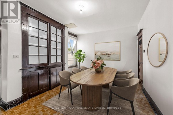 Dining room with an oval table, eight chairs, a large dark wood china cabinet, and a mirror. - 291 St Helen's Avenue, Toronto