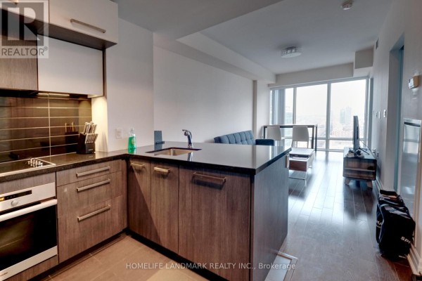 Open-concept living area with a kitchen island, sofa, dining table, and large windows. - 2910 - 8 The Esplanade, Toronto