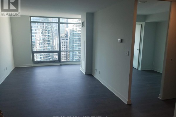 Living room with large windows overlooking the city, dark wood floors, and open doorway. - 2911 - 81 Navy Wharf Court, Toronto