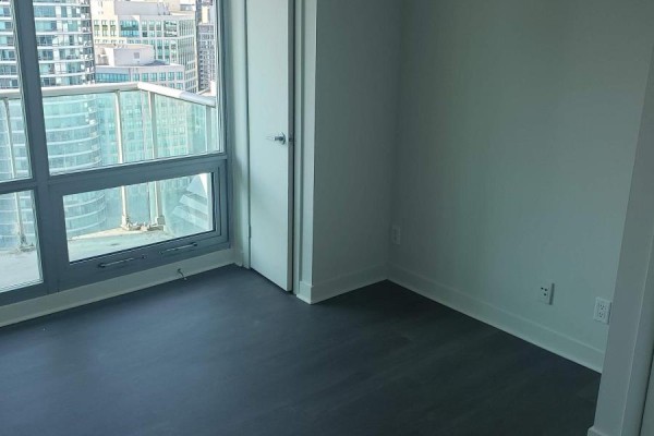 Bedroom with a large window, dark wood floors, and a closed door. - 2911 - 81 Navy Wharf Court, Toronto