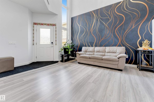 Living room with light grey wood-look flooring, a beige sofa, and a dark blue accent wall with gold lines. - 2912 12 Av Nw, Edmonton