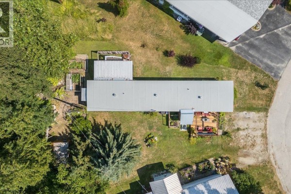 Top-down view of the property and mobile home, surrounded by trees and neighboring houses. - 2917 Georama Road Unit# 18, Nelson